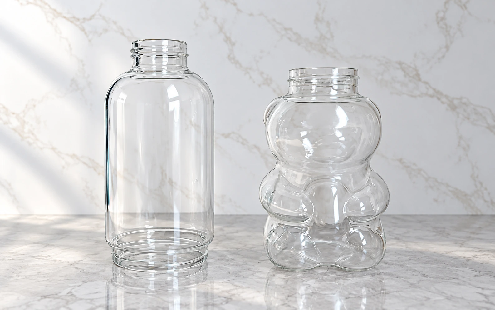 Clear borosilicate glass samples: a double-ended threaded glass body on the left and a bear-shaped bottle on the right